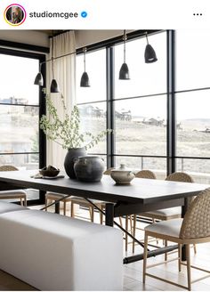 a dining room table with chairs and vases on top of it in front of large windows