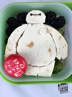 a lunch box with tortilla, fruit and blackberries in the shape of a teddy bear