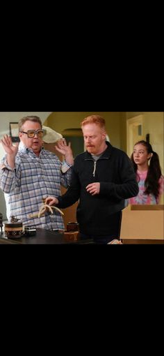 two men standing next to each other in front of a table with items on it