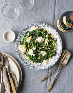 a bowl of food on top of a table next to silverware and utensils