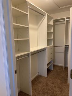 an empty walk in closet with white shelving