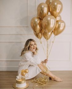 a woman sitting on the floor with gold balloons