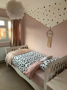 a small child's bed in a pink room with polka dots on the walls