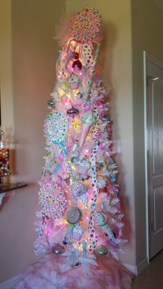 a pink and white christmas tree with lots of decorations