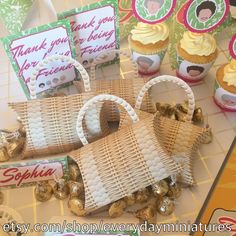 some cupcakes are sitting on a table with small baskets and tags in front of them