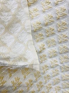 two white and yellow bedspreads with gold leaf designs on them, next to each other