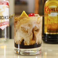 an alcoholic drink in a glass with ice and cherries