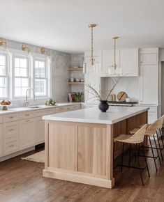 a large kitchen with white cabinets and wooden flooring is featured in this article by the interior design magazine