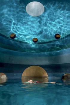 a man swimming in a pool with several circles around him and an object floating above the water