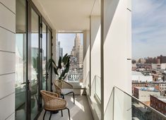 two wicker chairs sitting on top of a balcony next to a window with cityscape in the background