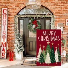 a merry christmas sign in front of a brick building with wreaths on the door