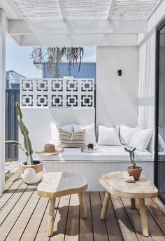 an outdoor living area with wooden floors and white furniture on the outside deck, along with potted cacti