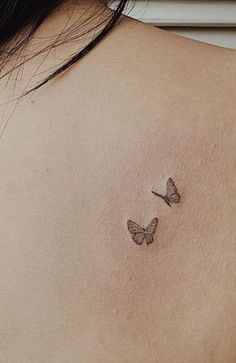 two butterflies on the back of a woman's shoulder