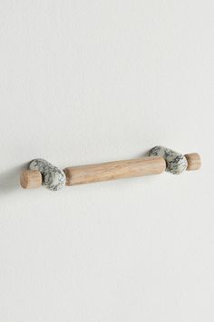 a white wall with two wooden pegs on it and some rocks in the middle