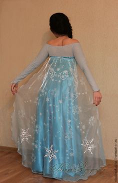 a woman in a blue dress with snowflakes on it is standing against a wall