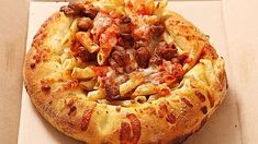 a pizza sitting on top of a box covered in cheese and meat toppings,