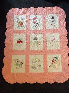 a pink and white quilt with pictures of animals on the front, along with an orange border