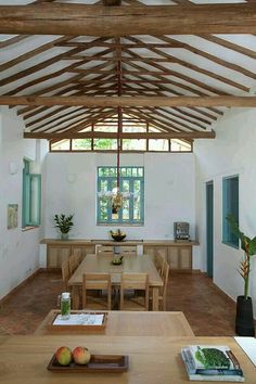 a dining room with wooden tables and chairs under a wood beamed ceiling that has windows