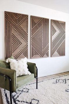 a green chair sitting in front of three wooden wall art pieces on a white wall