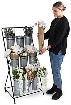 a woman standing next to a rack filled with flowers