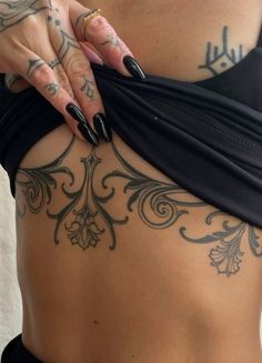 a woman with tattoos on her stomach holding onto the side of her body and wearing a black skirt