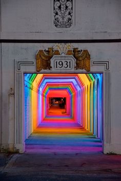 the entrance to a tunnel that is lit up with rainbow colors