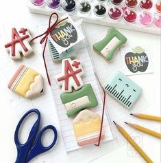 decorated cookies are sitting on a table next to scissors and markers