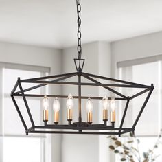 a chandelier with five candles hanging from it's centerpiece in a living room