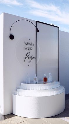 an outdoor fountain with bottles and glasses on it in front of a white wall that says, what's your poop?