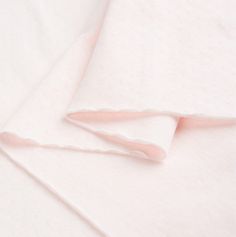 two sheets are folded on top of each other, one is pink and the other is white