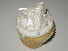 a cupcake with white frosting and a bow on top