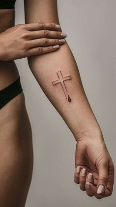 a woman's arm with a cross tattoo on the left side of her arm