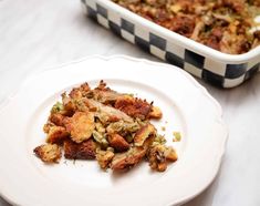 a white plate topped with food next to a casserole dish filled with stuffing