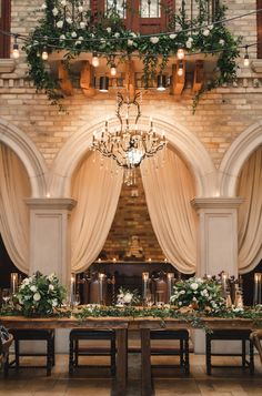 a table with flowers and greenery is set up in front of a chandelier