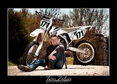 a man sitting on the ground next to a dirt bike