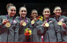 four women standing next to each other holding gold medals