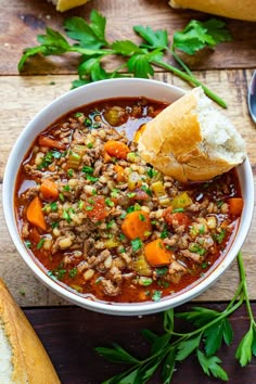 a bowl of soup with bread and parsley on the side, ready to be eaten