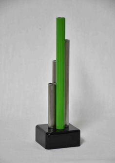 two tall green and silver vases sitting on top of a black stand against a white background