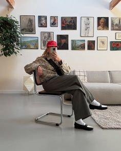 a woman sitting in a chair talking on a cell phone while wearing a red hat