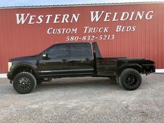 a black truck is parked in front of a red building with the words western welding custom truck beds on it