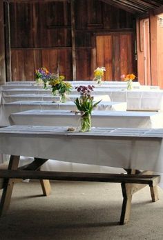 the tables are lined up with white linens and flowers in vases on them