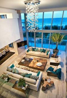 a living room filled with lots of furniture next to tall windows and a large chandelier