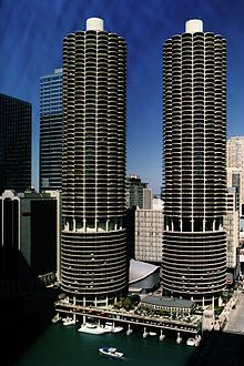 two tall buildings next to each other in the middle of a body of water with boats on it