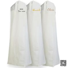 three white garment covers with gold lettering on the front and back, hanging from hooks