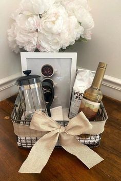 a basket filled with wine and other items on top of a wooden floor next to a vase