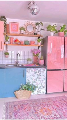 a pink and blue kitchen with plants on the shelves