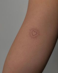 a woman's arm with a small heart tattoo on the left side of her arm