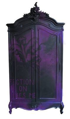 an ornate purple and black cabinet with writing on the door, in front of a dark background