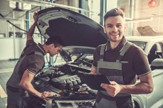 two mechanics working on the hood of a car