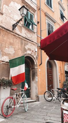 a bike parked in front of a building with an italian flag hanging from it's side